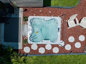 Ein Whirlpool, umgeben von weißen Stühlen und einer Terrasse mit Kiesweg.