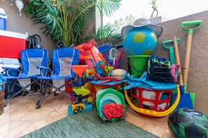 Eine Terrasse mit verschiedenen Kinderspielzeugen und Außenausrüstung, darunter ein Globus, Schaufeln und ein Spielzeugauto.