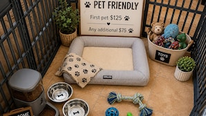 A pet-friendly area with a pet bed, bowls, toys, and a sign indicating pet fees.