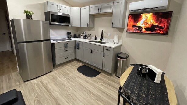 A modern kitchen with stainless steel appliances, grey cabinets, and a ceiling fan. - Cozy and comfortable tiny house  (Plant City)