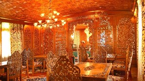 Um quarto ricamente decorado com detalhes em madeira elaborados, um lustre e um espelho grande.