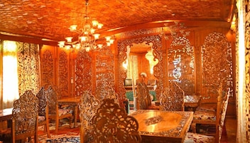 Um quarto ricamente decorado com detalhes em madeira elaborados, um lustre e um espelho grande.