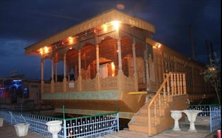 A building with a covered porch, a staircase leading to the entrance, and a fenced area with two planters.