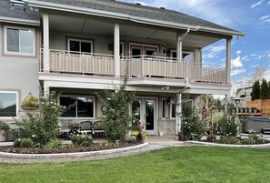 Una casa a due piani con un balcone, un portico e un giardino curato.