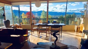 A modern living room with a large window offering a mountain view, wooden flooring, and contemporary furniture.