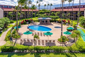 A hotel with a pool area, lounge chairs, and palm trees.