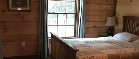 Una habitación con paneles de madera, una cama, una ventana con cortinas y un cuadro en la pared.