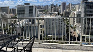 A balcony with a view of a cityscape, including high-rise buildings and a clear sky. - Pacific Monarch Top Floor Condo with Ocean, City and Mountain Views! (Honolulu)