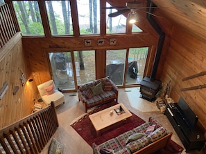 A cozy cabin interior with a wooden interior, a sofa, a coffee table, and a fireplace.