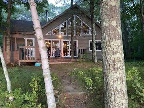 A cabin with a large front porch, multiple windows, and a chimney.