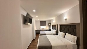 Een hotelkamer met twee bedden, een flatscreen televisie aan de muur en een bureau met stoel.