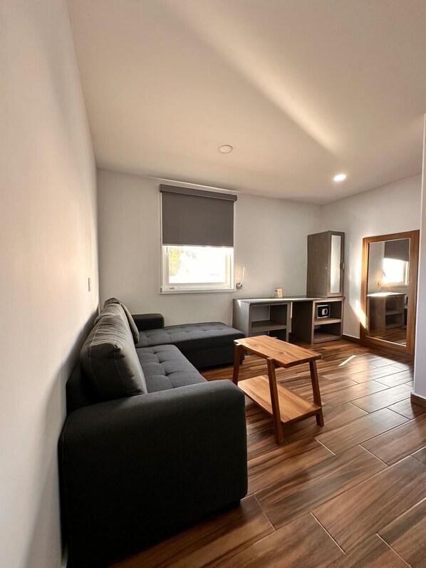 Una sala de estar moderna con un sofá seccional, una mesa de centro de madera y un mueble bajo para la televisión.