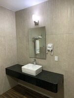 Un baño con lavamanos blanco, un espejo, toallero y secador de pelo.