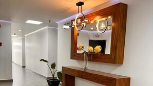 Een moderne receptie met een houten console, een spiegel en een kamerplant.
