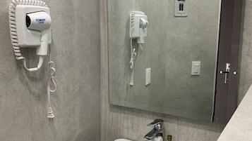 A bathroom with a white sink, a hairdryer mounted on the wall, and a mirror above the sink.