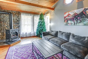 Una sala de estar acogedora con chimenea de piedra, un sofá, una mesita de centro y un árbol de Navidad.
