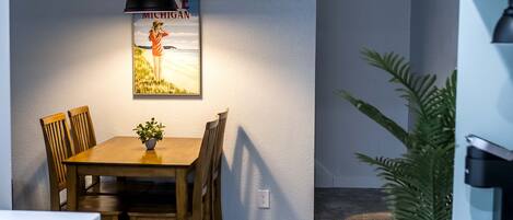 Un comedor con mesa y sillas de madera, una lámpara colgante y un cartel en la pared.