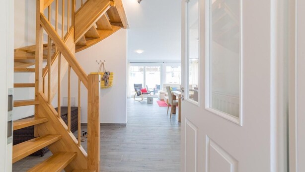 Um interior moderno com escada de madeira que dá acesso a uma sala de estar.