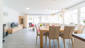 Uma sala de estar moderna com área de jantar, janelas amplas e lareira.