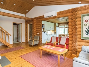 A log cabin interior with a wooden staircase, a dining area with a table and chairs, and a kitchen visible through an open door. - Lahukka by Interhome (Puumala)