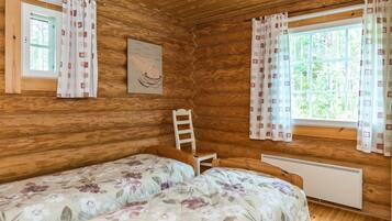 Una cabaña con dos camas, paredes de madera, una escalera, una ventana con cortinas y un radiador.