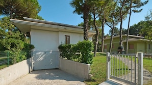 A two-story building with a white exterior, a small porch, and a gated entrance. - Wonderful  villa for 8 people with A/C, TV, terrace and pets allowed (Lignano Sabbiadoro)
