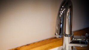 Ein weißes Waschbecken mit chromfarbenem Wasserhahn und Abfluss.