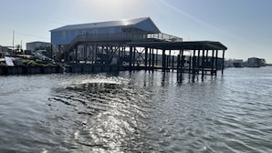 Une propriété située au bord de l’eau, avec une grande maison et une jetée en bois qui s’avance dans l’eau.