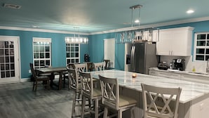 Une cuisine moderne dotée d’un grand îlot central, de meubles blancs et d’un mur d’accent de couleur turquoise.