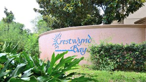 Ein Schild für CrestWynd Bay mit Sonnensymbol, umgeben von üppigem Grün.