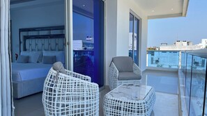Relax on the balcony with a comfortable seating area, featuring a bed and two wicker chairs.