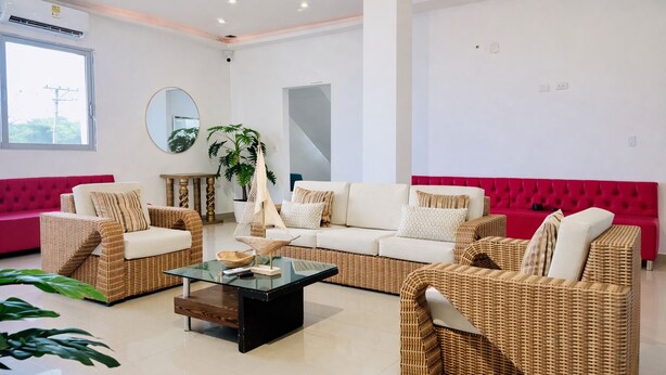 A modern living room with wicker furniture, a glass coffee table, and a red sofa. - exclusive beach mansion (La Boquilla)