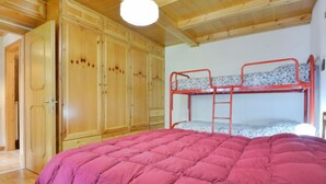 Ein Zimmer mit Etagenbett, Holzschrank und Deckenventilator.