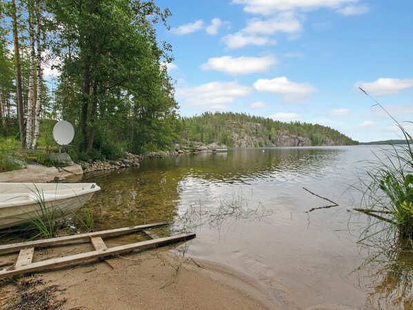 A calm lake with a dock and boats, surrounded by trees and a clear sky.