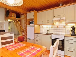 A kitchen with wooden cabinets, a microwave, a stove, and a sink. - Vacation home Ulappa by Interhome (Puumala)