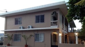 Un edificio de dos pisos con techo plano, varias ventanas con rejas y una entrada con portón.