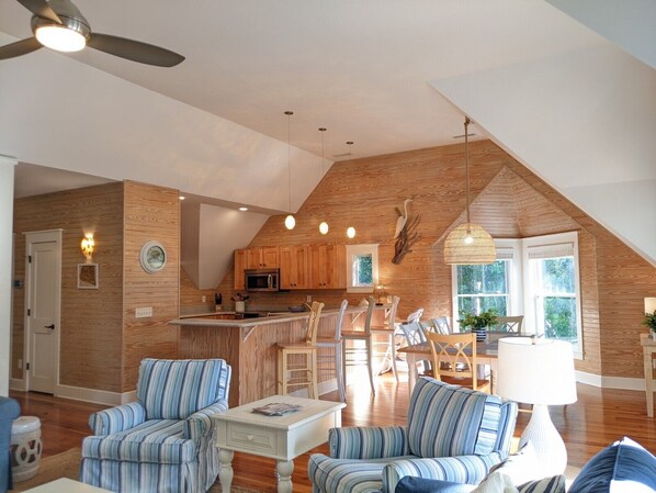 Relax in a spacious living area with a high ceiling and exposed beams, featuring a dining space and modern kitchen.