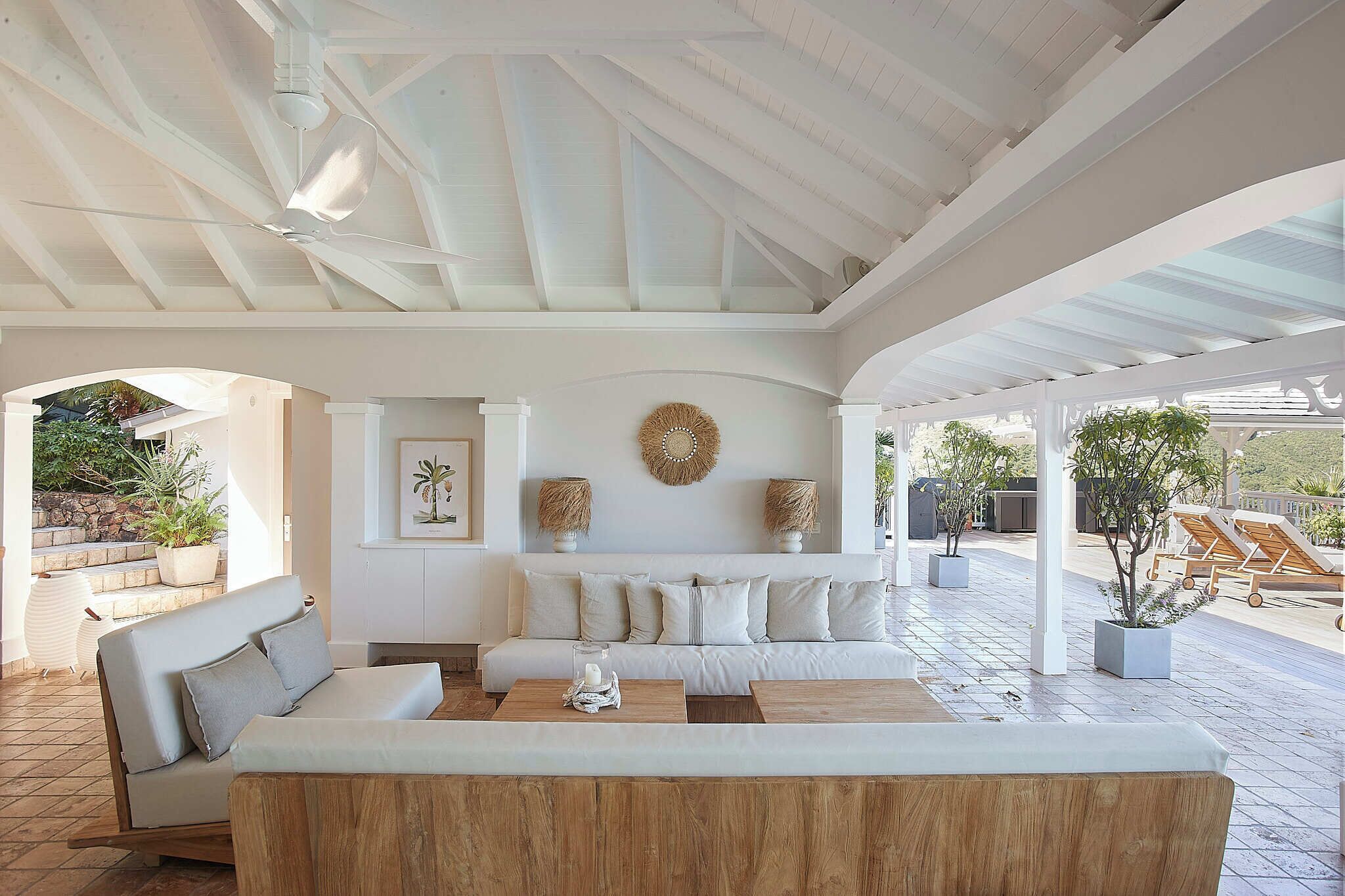 A spacious patio area with a white sofa, wooden coffee table, and potted plants.
