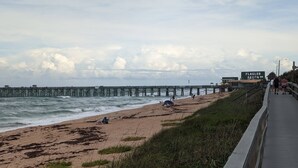 A beach with a pier extending into the ocean, a boardwalk, and a sign for Flagler Beach. - Sandy Toes Paradise (Palm Coast)