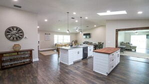 A spacious kitchen with white cabinetry, a central island, and pendant lighting. - Sandy Toes Paradise (Palm Coast)