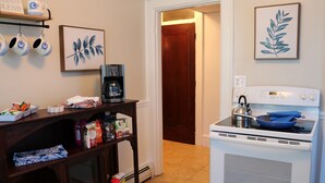 A kitchen with a coffee maker, a stove, and various kitchen items on shelves. - 🤓Clever Studio🍷Free Wine☕️Coffee / Tea Bar - Free Parking! (Dover)