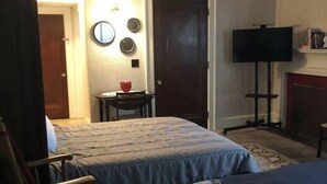 A hotel room with two beds, a small table, a chair, a television, and a fireplace. - 🤓Clever Studio🍷Free Wine☕️Coffee / Tea Bar - Free Parking! (Dover)