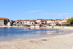 Stroll through a tranquil waterfront square surrounded by traditional buildings with red-tiled roofs.