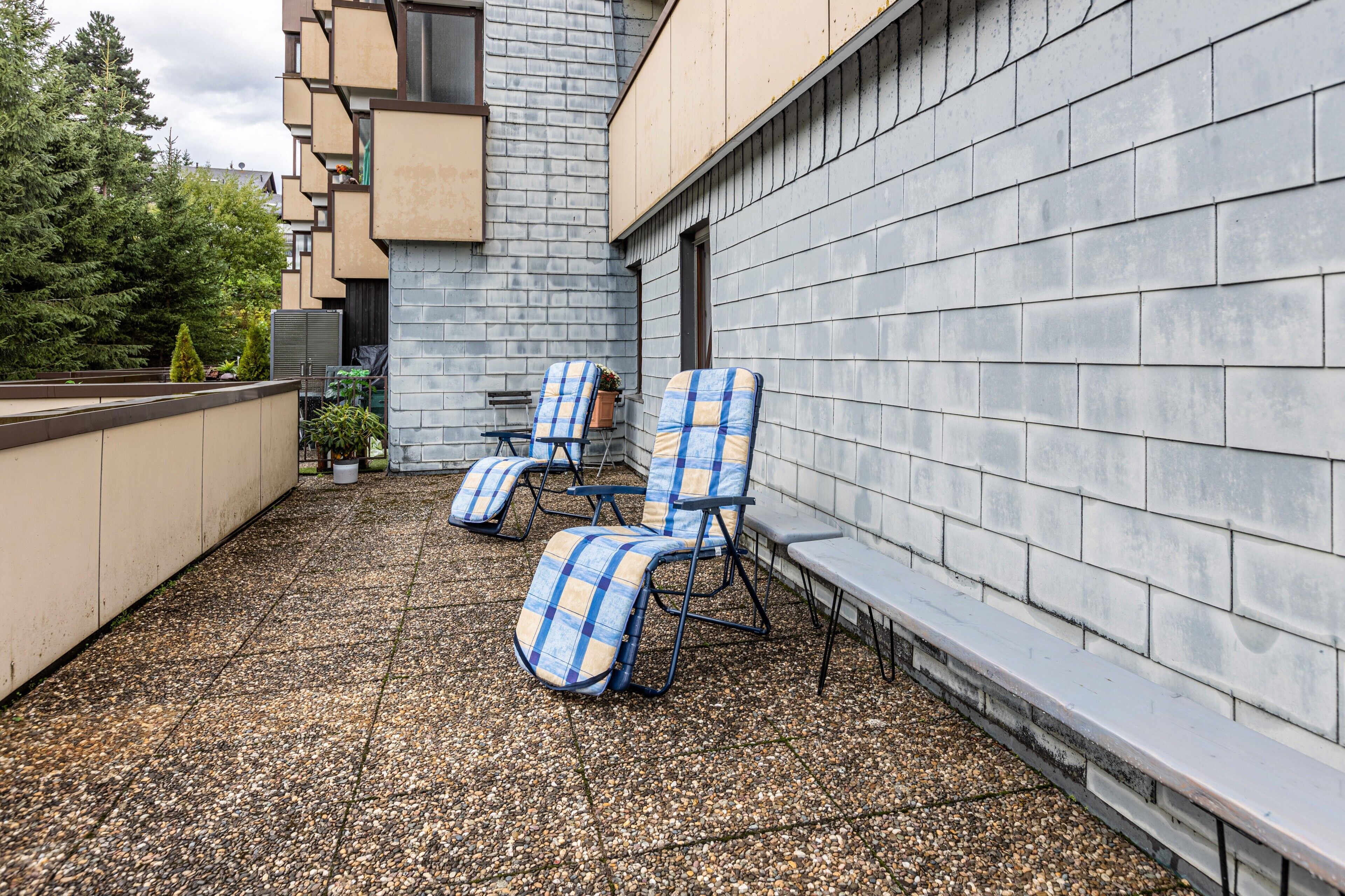 Una terrazza sul tetto con due poltrone, un tavolino e una pianta in vaso.