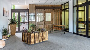 Un hall d’entrée avec un banc en bois, des plantes en pot et un grand bac à fleurs.