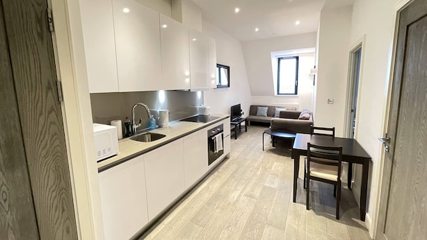 Eine moderne Küche mit weißen Schränken, einem eingebauten Backofen und einem Essbereich mit Tisch und Stühlen.