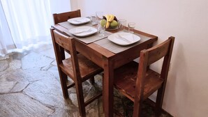 Un tavolo da pranzo in legno apparecchiato con piatti, posate e bicchieri, insieme a una ciotola di frutta e una bottiglia d'acqua.