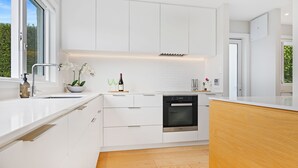 A modern kitchen with white cabinetry, a built-in oven, and a wooden countertop.