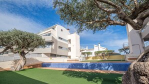 Un edificio moderno con balconi, una piscina e un prato curato.