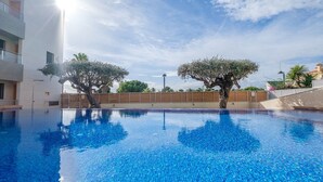 Una piscina con acqua cristallina e blu, circondata da alberi e un edificio.